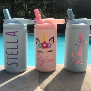 Puede incluir: Tres botellas de agua de acero inoxidable personalizadas con tapas de pajita. Las botellas son azul claro, rosa y azul claro. Los nombres Stella, Rylee y Kaelyn est&aacute;n escritos en las botellas con letras moradas, rosas y rosas. La botella rosa tiene un dise&ntilde;o de unicornio con flores.