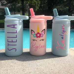 Puede incluir: Tres botellas de agua de acero inoxidable personalizadas con pajitas. Las botellas son de color azul claro, rosa y azul claro. Los nombres Stella, Rylee y Kaelinn est&aacute;n impresos en las botellas en color morado, rosa y purpurina rosa, respectivamente. La botella del medio tiene un dise&ntilde;o de unicornio con flores y un fondo rosa.
