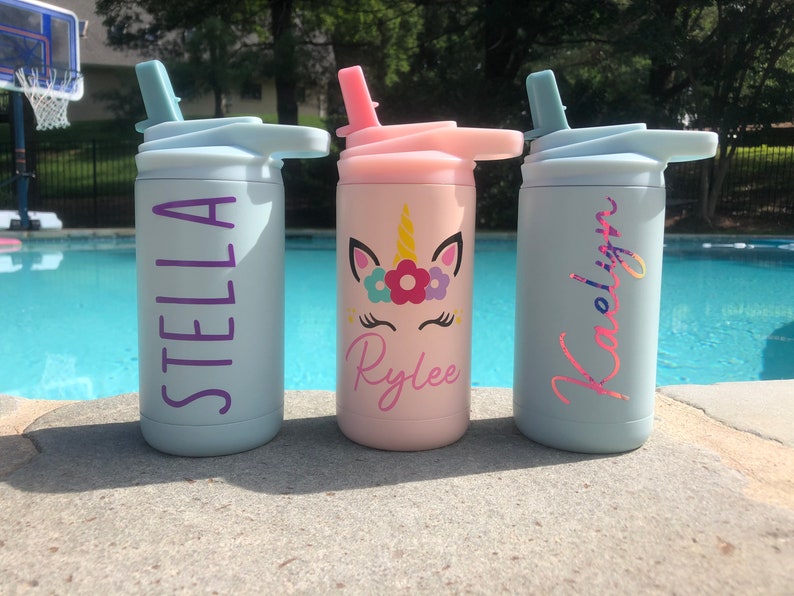 Puede incluir: Tres botellas de agua de acero inoxidable personalizadas con pajitas. Las botellas son de color azul claro, rosa y azul claro. Los nombres Stella, Rylee y Kaelinn est&aacute;n impresos en las botellas en color morado, rosa y purpurina rosa, respectivamente. La botella del medio tiene un dise&ntilde;o de unicornio con flores y un fondo rosa.