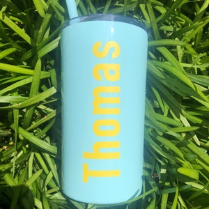 May include: A light blue tumbler with a yellow straw and the name "Thomas" printed in yellow on the side.