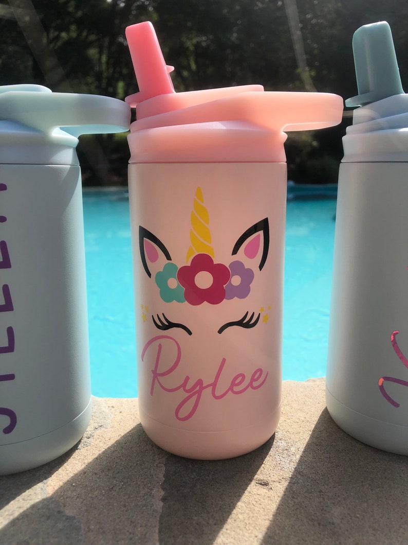Puede incluir: Botella de agua de acero inoxidable rosa con un dise&ntilde;o de unicornio y el nombre "Rylee" en ella. La botella tiene una tapa con pajita y un asa de transporte.