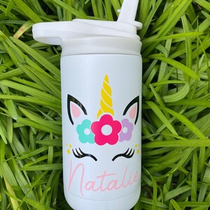 Puede incluir: Botella de agua de acero inoxidable blanca con un dise&ntilde;o de unicornio y el nombre "Natalie" en la parte delantera. La botella tiene una tapa blanca con una pajita.