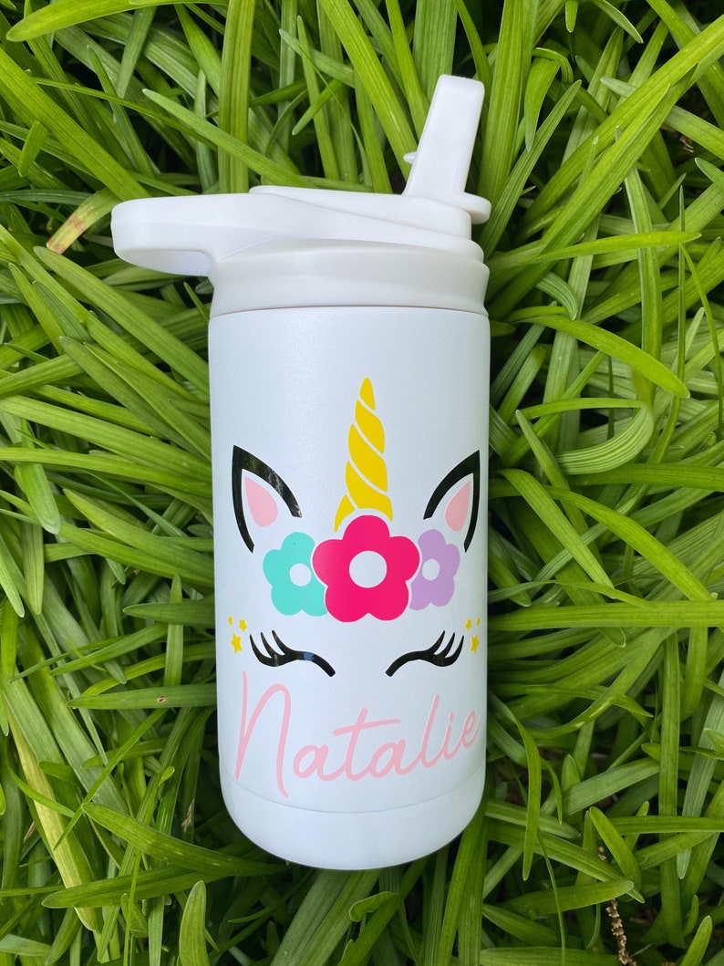 Puede incluir: Botella de agua de acero inoxidable blanca con un dise&ntilde;o de unicornio y el nombre "Natalie" en la parte delantera. La botella tiene una tapa blanca con una pajita.