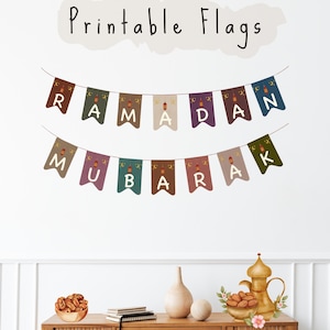 May include: Two strings of colorful pennant flags spelling "Ramadan Mubarak" hang on a white wall. The flags are decorated with crescent moons and lanterns. The words "Printable Flags" are written above the flags.