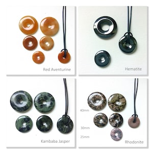 May include: Assortment of gemstone donut pendants with black cords.  The stones are red aventurine, hematite, kambaba jasper, and rhodonite.  The pendants are available in various sizes, including 25mm, 30mm, and 40mm.