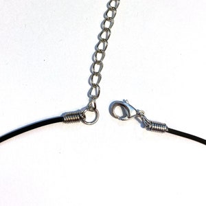 May include: A black cord necklace with a silver spring clasp and a silver chain extension.
