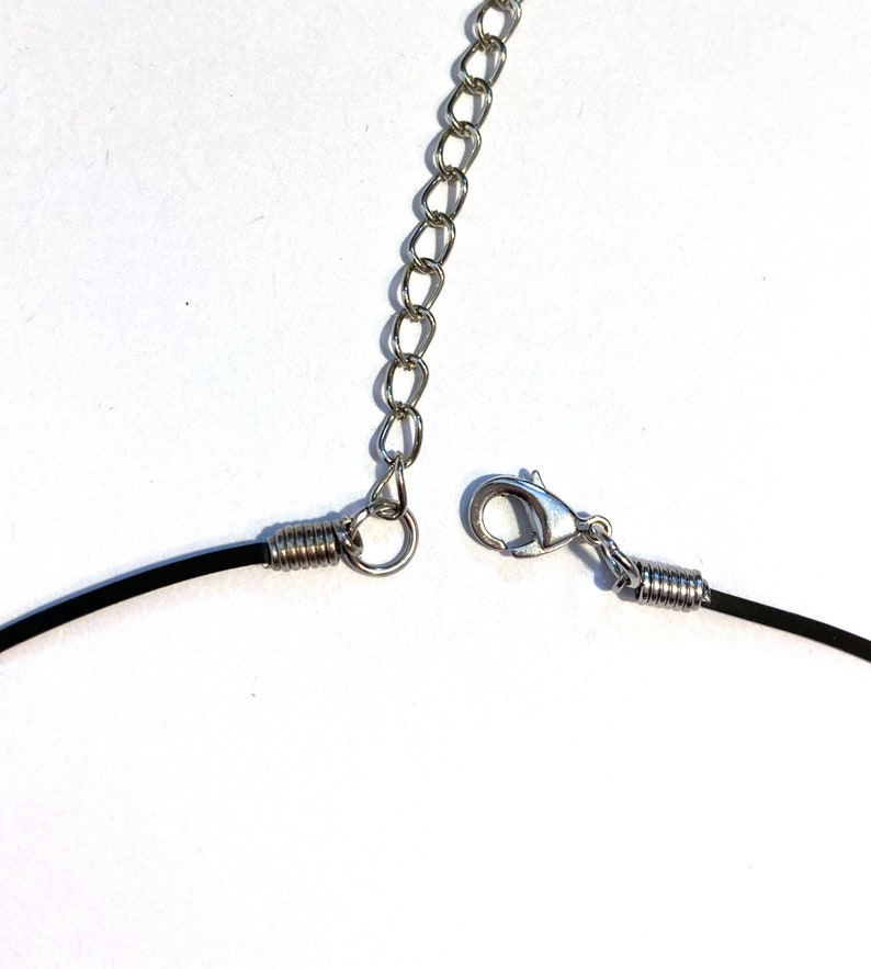 May include: A black cord necklace with a silver spring clasp and a silver chain extension.