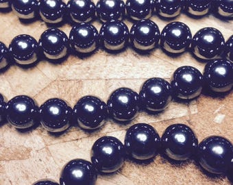 May include: A strand of black hematite beads. The beads are round and smooth, and they are strung on a clear thread.