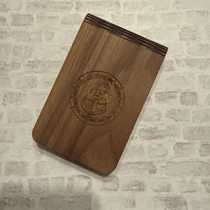 May include: A wooden notebook with a compass and anchor design engraved on the front. The design includes the text "USN".