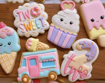 May include: Assortment of decorated sugar cookies in pastel colors. Cookies include ice cream cones, ice cream trucks, cupcakes, and number two shapes. Some cookies have the words "Two Sweet" written on them.