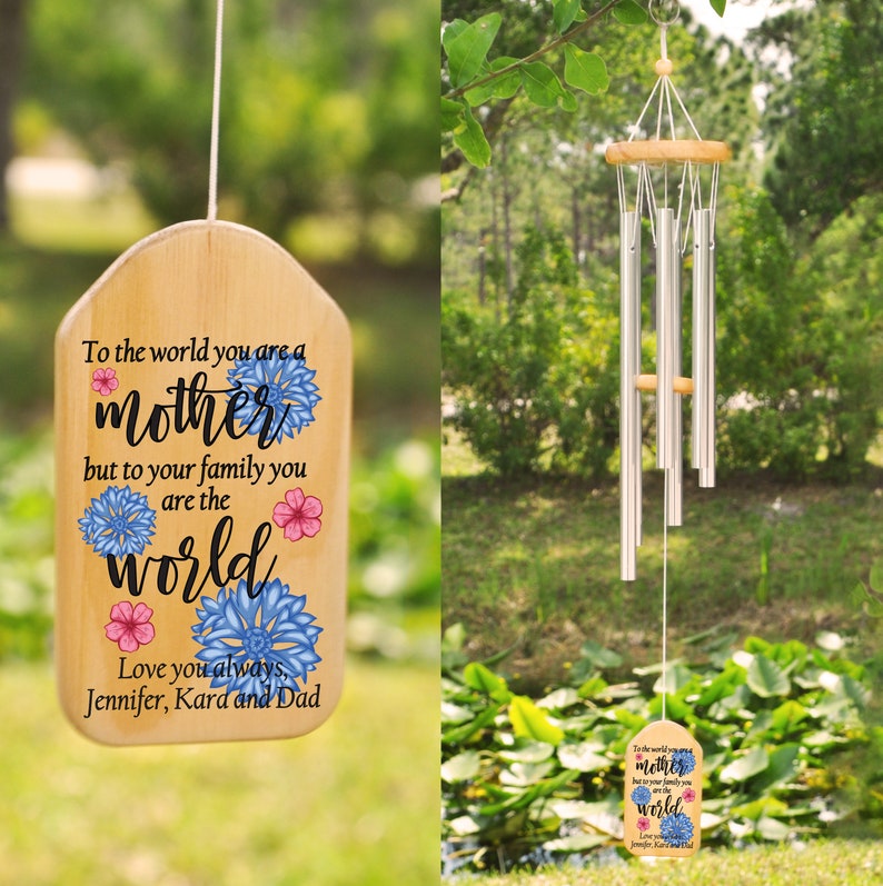 A silver wind chime with brown wood and a design with black text and pink and blue flowers