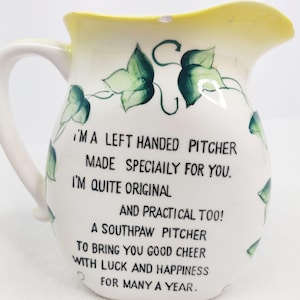 May include: White ceramic pitcher with a green ivy design and a yellow rim. The pitcher has a quote that reads: "I'ma left handed pitcher made specially for you. I'm quite original and practical too! A southpaw pitcher to bring you good cheer with luck and happiness for many a year."