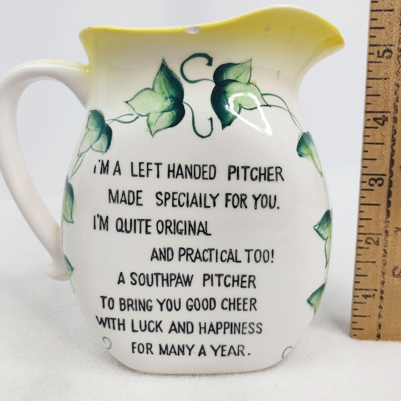 May include: White ceramic pitcher with a green ivy design and the text "I'MA LEFT HANDED PITCHER MADE SPECIAILY FOR YOU. I'M QUITE ORIGINAL AND PRACTICAL TOO! A SOUTHPAW PITCHER TO BRING YOU GOOD CHEER WITH LUCK AND HAPPINESS FOR MANY A YEAR."