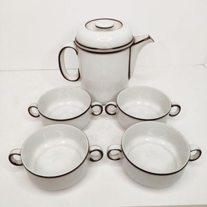 Puede incluir: Una cafetera de cerámica blanca con un borde marrón y cuatro cuencos de cerámica blanca a juego con un borde marrón.