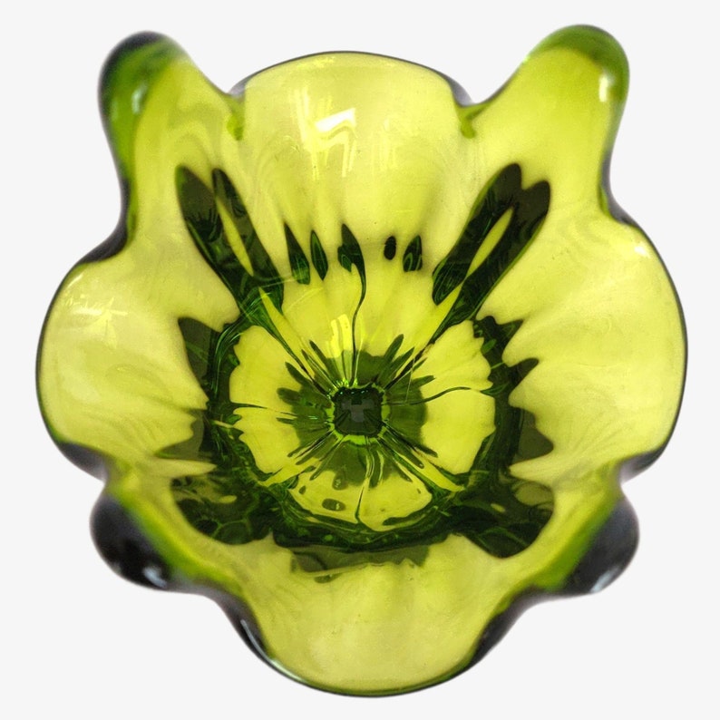 May include: A green glass vase with a flower-like shape. The vase has a wide opening and a narrow neck.