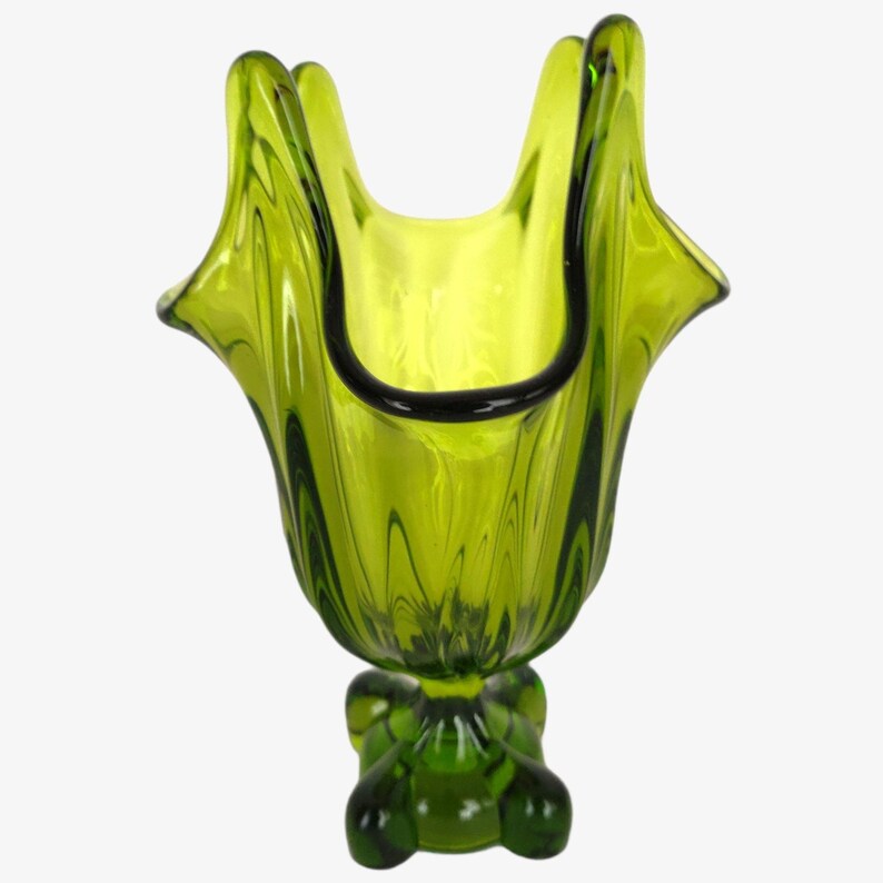 May include: A green glass vase with a unique, ruffled design and a four-legged base.