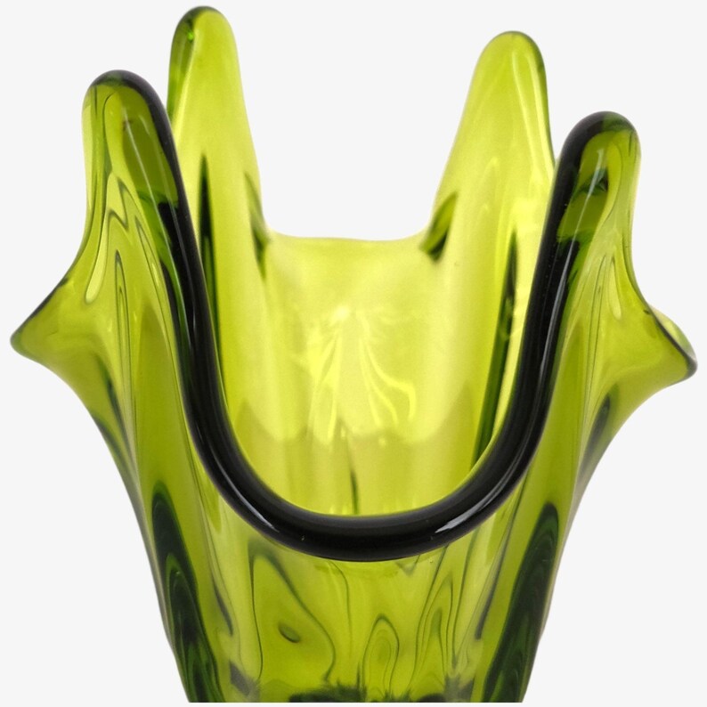 May include: A green glass vase with a unique, wavy design. The vase has a wide opening and a narrow base.