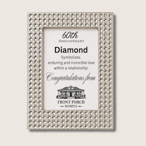 Puede incluir: Un marco de fotos rectangular con un borde plateado incrustado con numerosos cristales transparentes facetados. El inserto presenta texto negro que dice 60th Anniversary Diamond Symbolizes enduring and invincible love within a relationship Congratulations from Front Porch Homes con una ilustración de una casa.