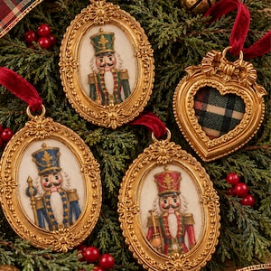 May include: Four gold-toned hanging ornaments with ornate frames. Three are oval-shaped, each featuring a painted nutcracker figure in a different uniform. One is heart-shaped with a red, green, and black plaid fabric insert. Each has a red velvet ribbon.