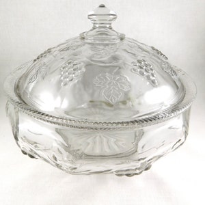 May include: A clear glass serving bowl with a lid. The bowl and lid are decorated with a grapevine pattern.
