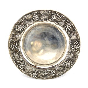 May include: A silver serving dish with a raised design of grapes and leaves around the rim.