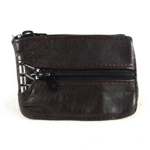 May include: A brown leather zippered coin purse with a silver zipper pull.