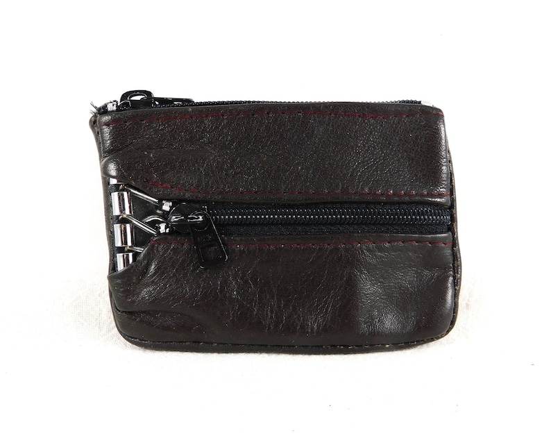 May include: A brown leather zippered coin purse with a silver zipper pull.