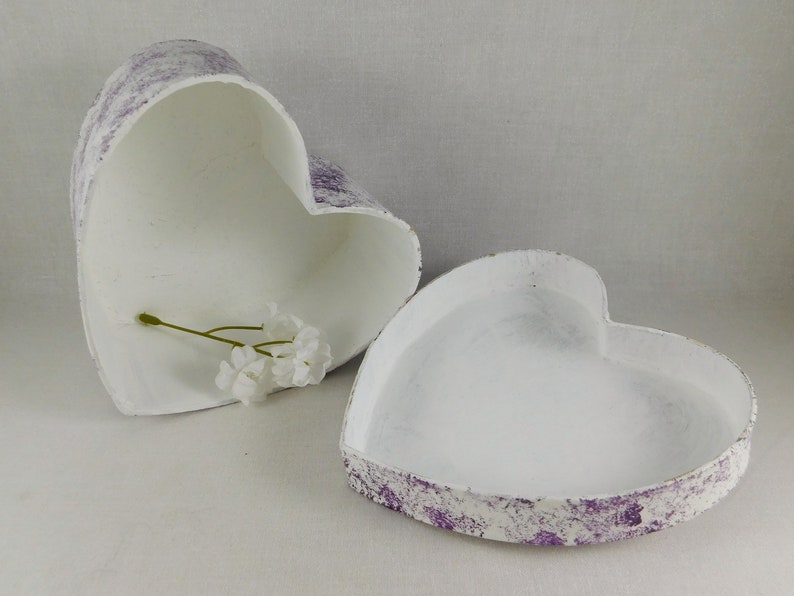 Op de afbeelding: Twee witte hartvormige dozen met een paars splatter-ontwerp. De bovenkant is open en er zit een klein takje witte bloemen in.
