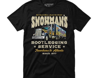 May include: Black t-shirt featuring a graphic of a semi-truck with the text "SNOWMAN'S BOOTLEGGING SERVICE Texarkana to Atlanta SINCE 1977". The truck has a colorful mural on the trailer.