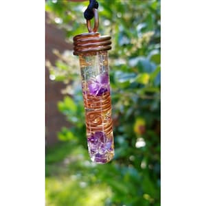 May include: A copper wire wrapped pendant with amethyst crystals inside a clear glass tube.