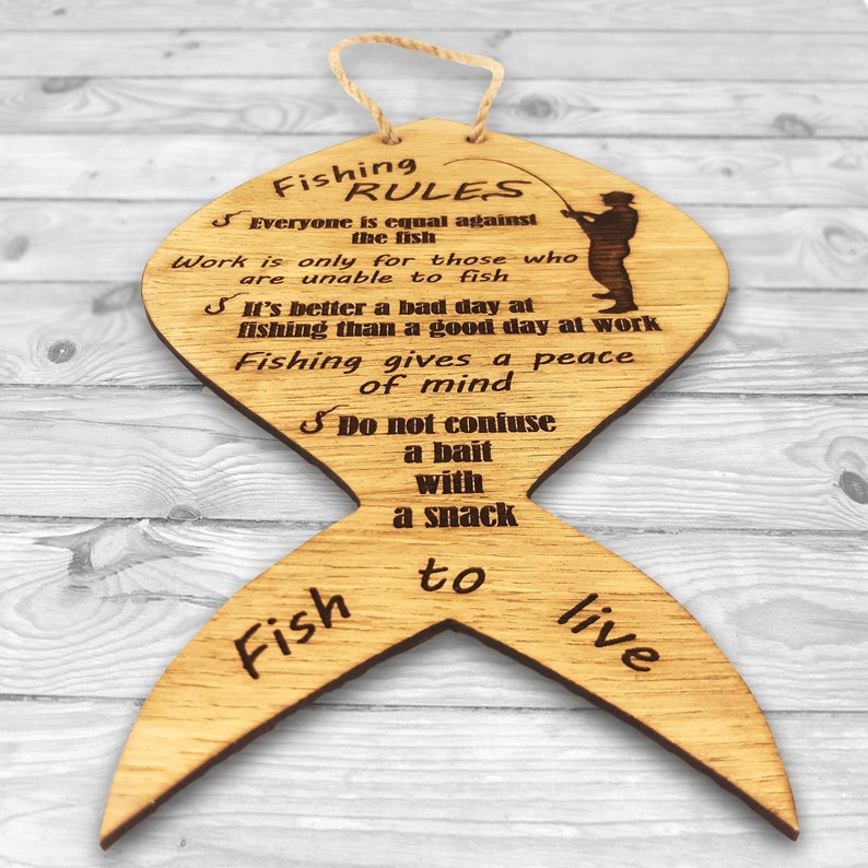 Zoomed part of the rules. The fishing rules are made of wood. The laser-cut fish-shaped board is engraved with various fishing rules. The rules come with a linen cord for hanging.