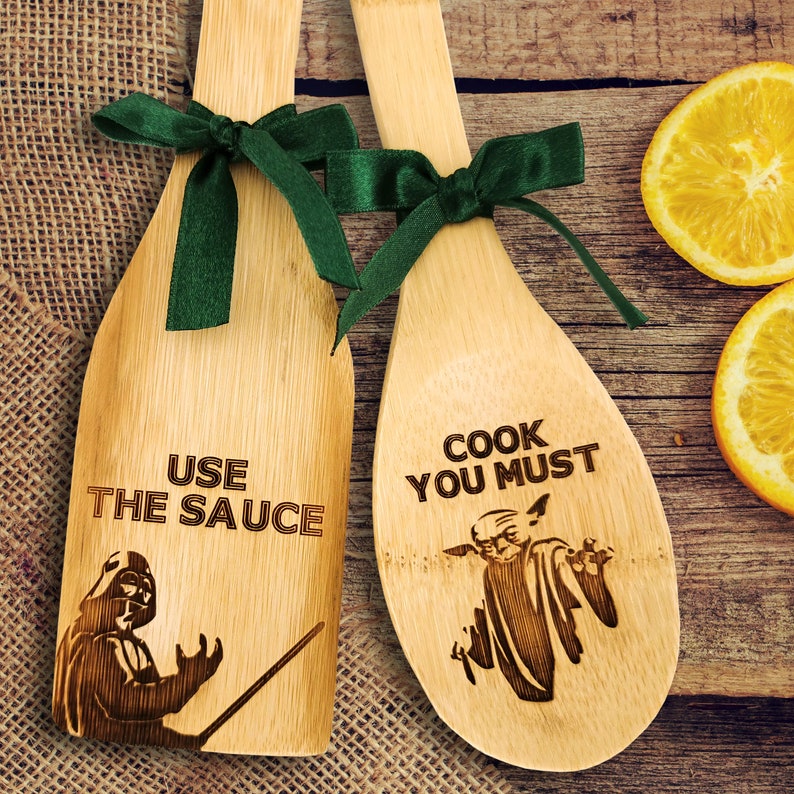 Wooden spatula and spoon set. Wooden spoon on the right. The spoon is engraved with Baby Yoda and the inscription - cook you must. Spatula on the left. The spatula is engraved with Darth Vader and the inscription - Use the sauce.