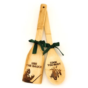 Wooden spatula and spoon set. Wooden spoon on the right. The spoon is engraved with Baby Yoda and the inscription - cook you must. Spatula on the left. The spatula is engraved with Darth Vader and the inscription - Use the sauce.