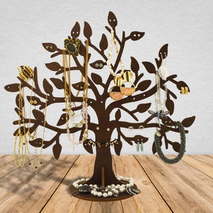 The dark brown jewelry holder tree is made of wood. There are earrings, chains, rings, bracelets hanging on the jewelry tree.