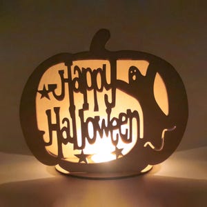 May include: A wooden pumpkin-shaped candle holder with a cutout design of a ghost and the words "Happy Halloween".