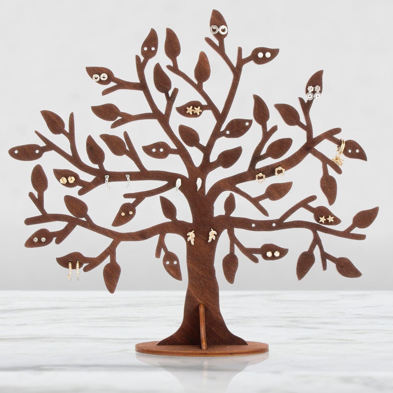 The dark brown tree of the jewelry holder is made of wood. Earrings hang from a laser-cut tree.