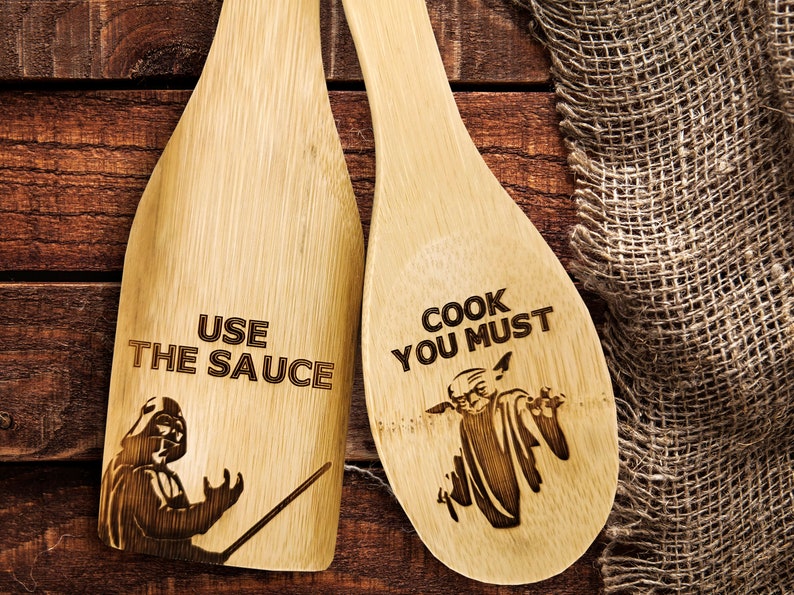 Wooden spatula and spoon set. Wooden spoon on the right. The spoon is engraved with Baby Yoda and the inscription - cook you must. Spatula on the left. The spatula is engraved with Darth Vader and the inscription - Use the sauce.