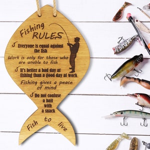 Next to fishing tackle is a board with fishing rules. The fishing rules are made of wood. The laser-cut fish-shaped board is engraved with various fishing rules. The rules come with a linen cord for hanging.