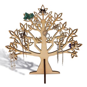 The light brown tree of the jewelry holder is made of wood. Earrings hang from a laser-cut tree.