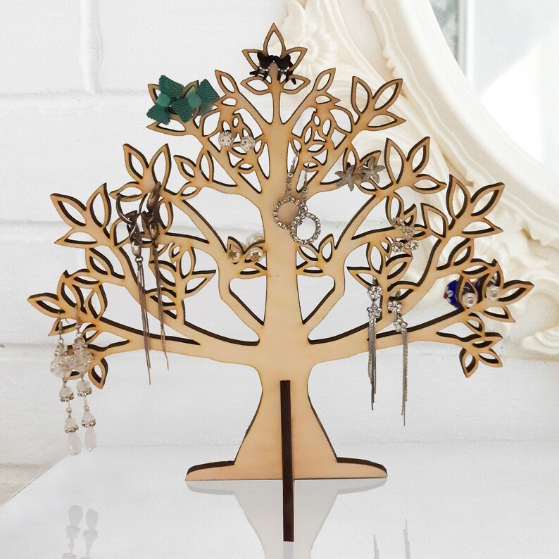 The light brown tree of the jewelry holder is made of wood. Earrings hang from a laser-cut tree.