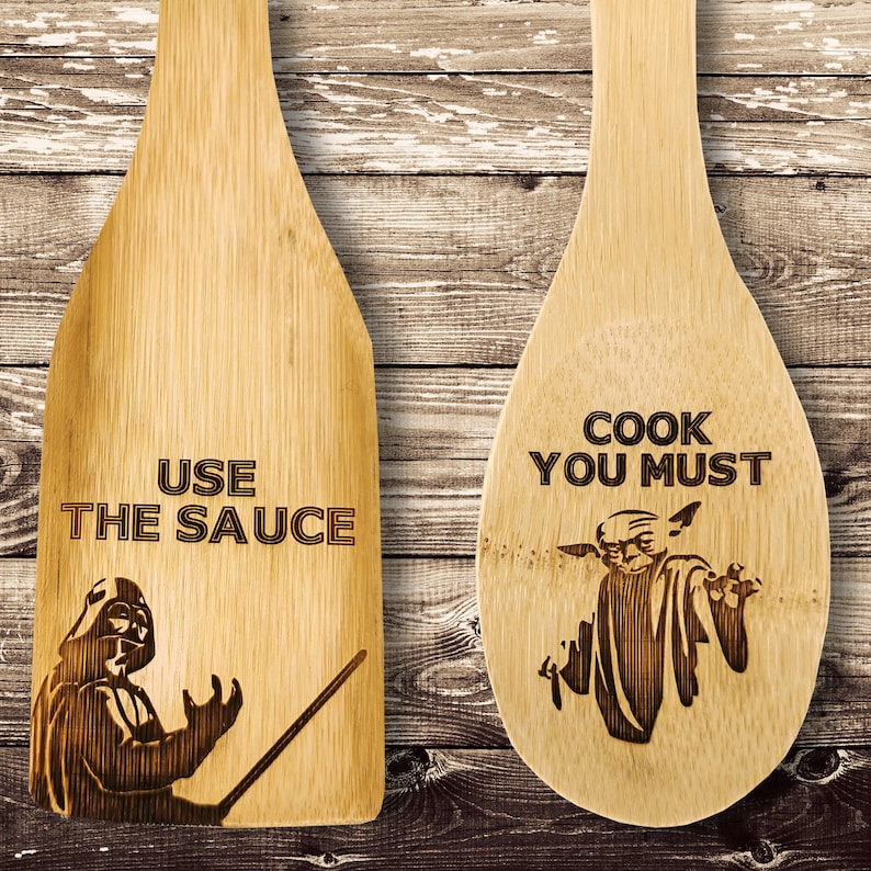 Wooden spatula and spoon set. Wooden spoon on the right. The spoon is engraved with Baby Yoda and the inscription - cook you must. Spatula on the left. The spatula is engraved with Darth Vader and the inscription - Use the sauce.