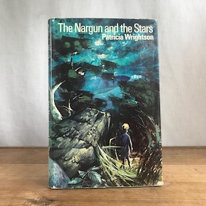 May include: A book cover featuring a blue and green illustration of a boy standing in a forest at night. The title of the book is "The Nargun and the Stars" by Patricia Wrightson.