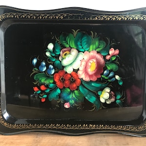 May include: Black metal tray with a gold trim and a hand-painted floral design featuring pink, red, white, and blue flowers.