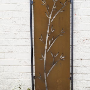 May include: A rusty brown metal garden screen with a cut-out design of a bamboo plant. The screen is framed in black metal and has a rustic look.