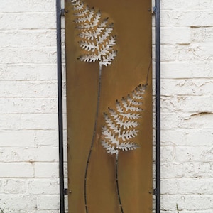 May include: A metal garden screen with a rusty brown finish and two fern designs cut out in the metal. The screen is framed in black metal.