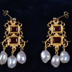 May include: Gold earrings with two red gemstone accents and three pearl drops.