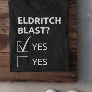 Könnte beinhalten: Schwarzes T-Shirt mit weißem Text, der "Eldritch Blast?" lautet, mit zwei Kontrollkästchen darunter, eines angekreuzt und eines nicht angekreuzt. Der Text unter den Kontrollkästchen lautet "YES".