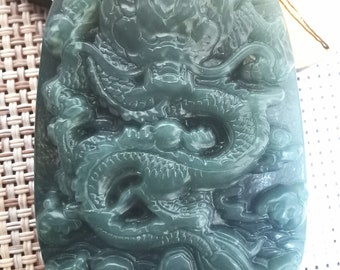 Op de afbeelding: Een jade hanger gegraveerd met een gedetailleerd drakenontwerp. De hanger is diep groen van kleur en heeft een gladde, gepolijste afwerking.