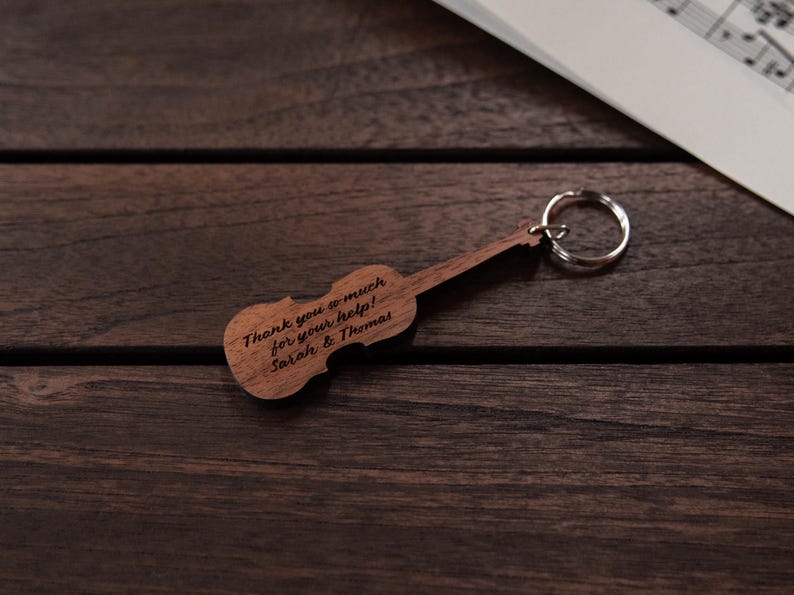 Puede incluir: Llavero de viol&iacute;n de madera con un mensaje personalizado: "&iexcl;Muchas gracias por tu ayuda! Sarah & Thomas".