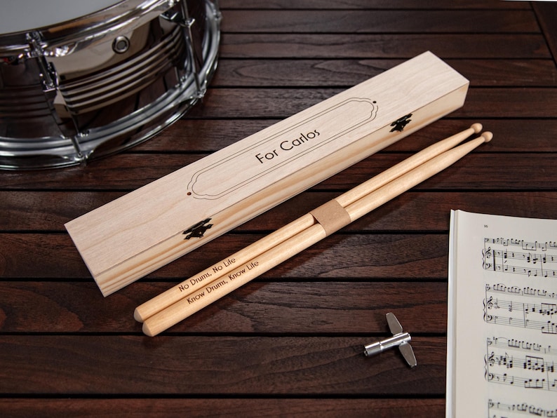 May include: A wooden box with a personalized inscription "For Carlos" and a pair of wooden drumsticks with the engraved text "No Drum, No Life. Know Drum, Know Life."